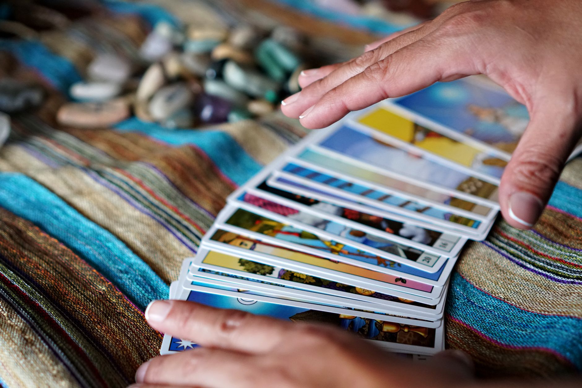 Mains posant une carte de tarot sur une table en bois clair, lumière du matin